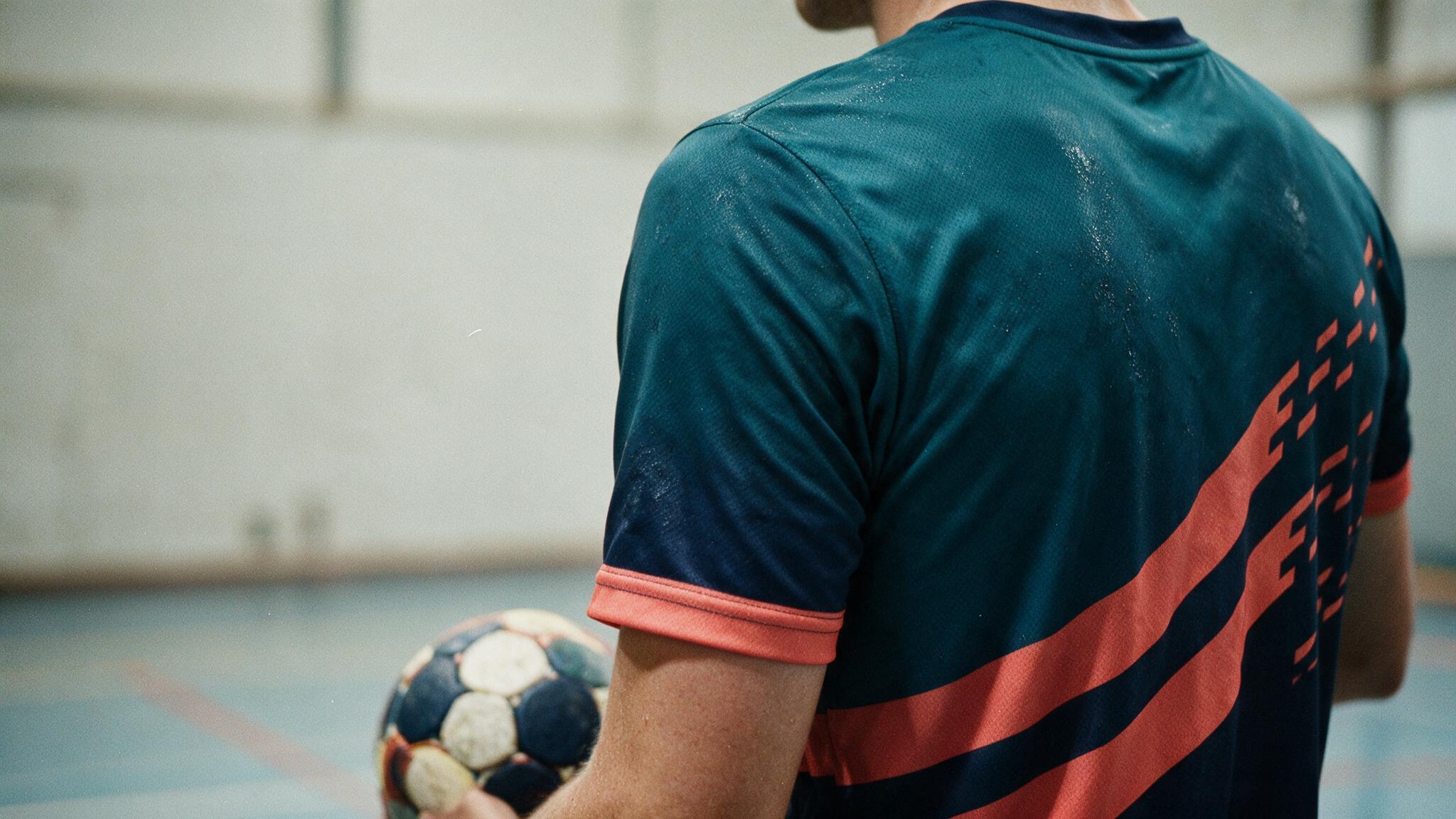 Gros plan sur un maillot de handball personnalisé en sublimation intégrale, motif intégré dans la fibre, joueur ballon en main