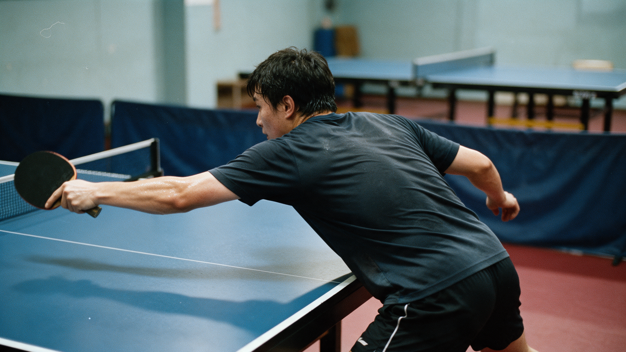 Joueur de tennis de table en pleine frappe lors d'un entraînement en club