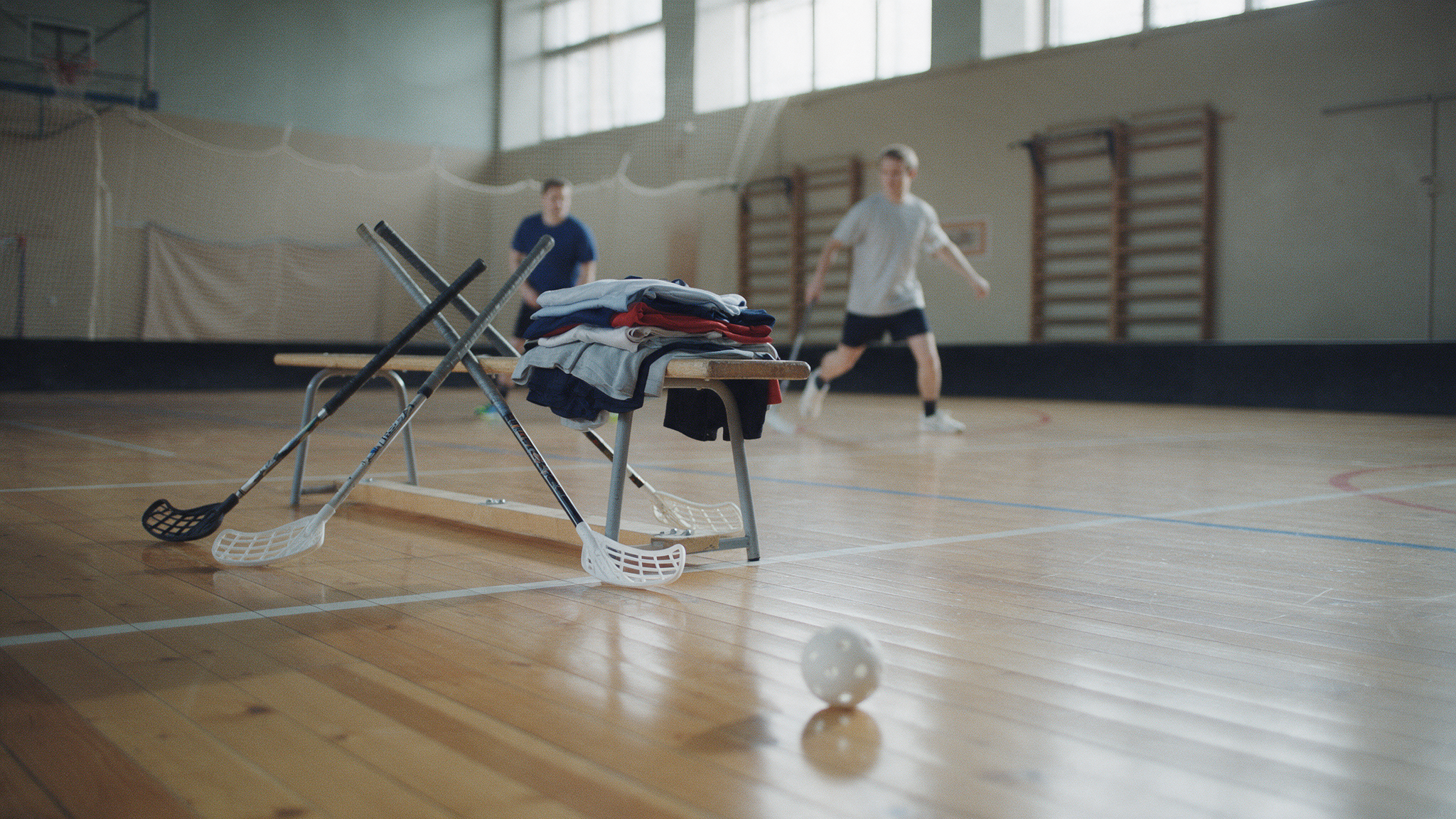 Crosses et maillots de floorball personnalisés posés sur un banc dans une salle de sport avant l'entraînement