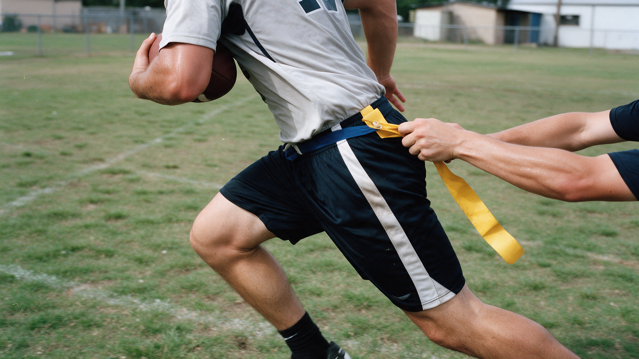 Joueur de flag football courant avec le ballon, un adversaire arrachant le fanion de sa ceinture
